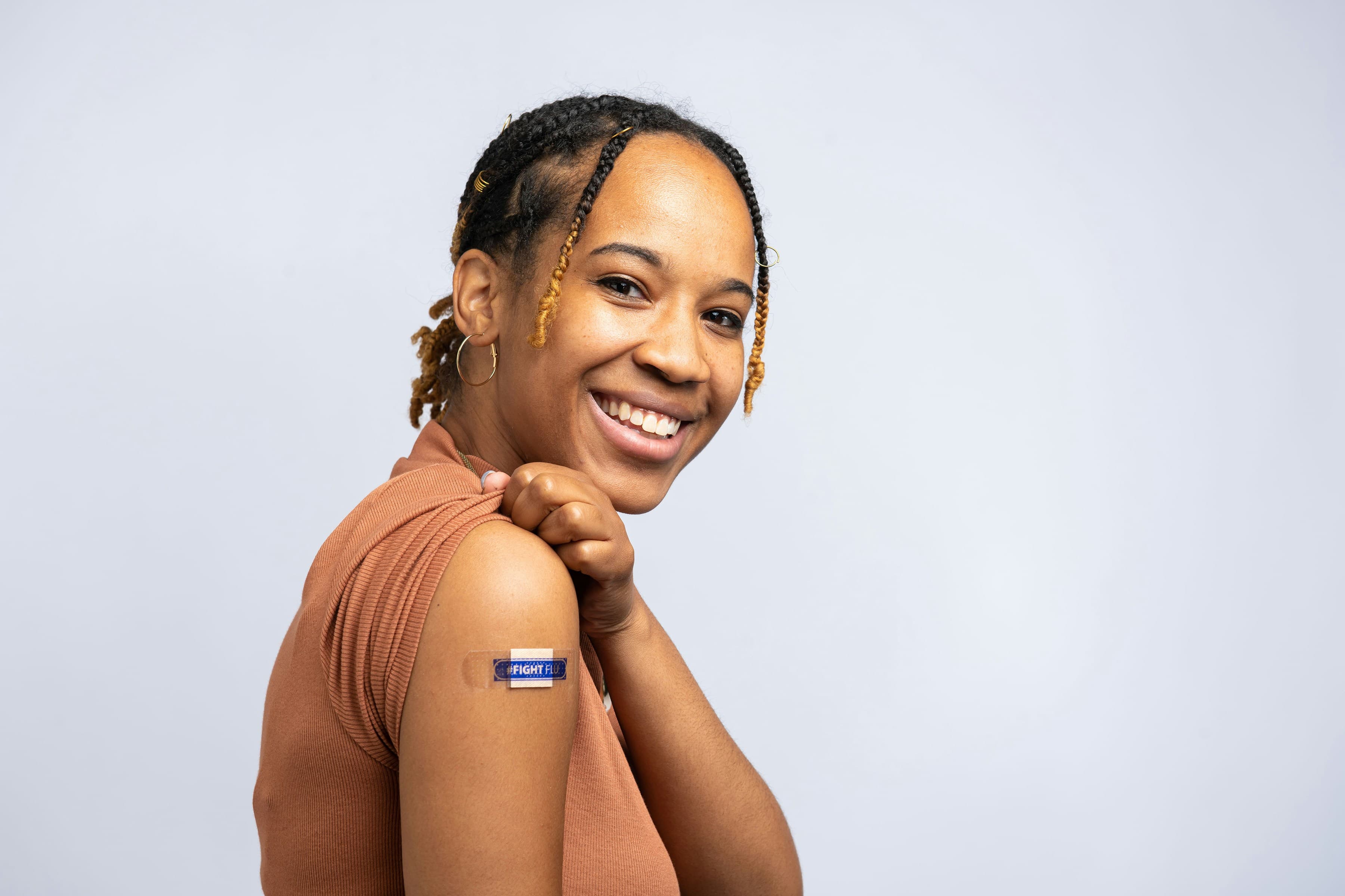 A smiling patient showing their vaccine bandage